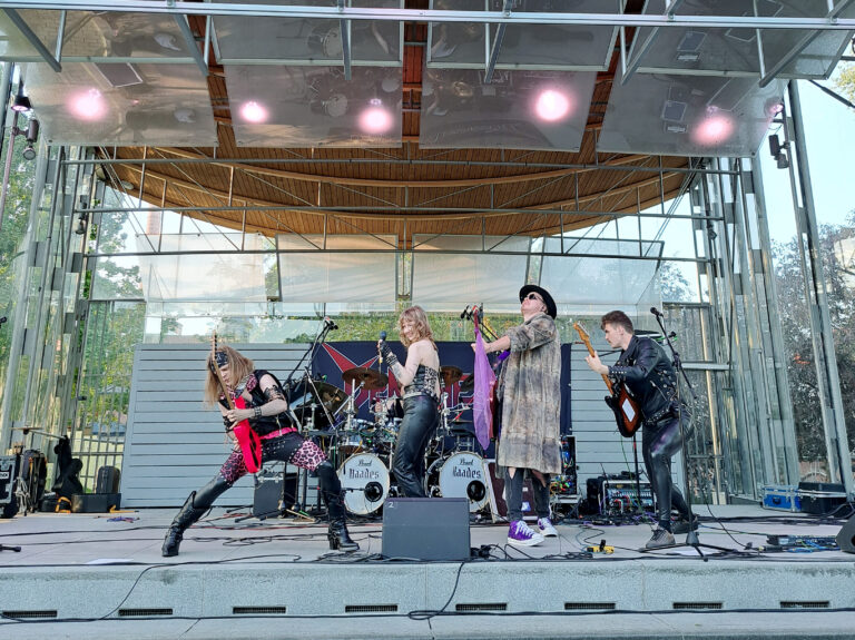 Viisihenkinen rock-yhtye esiintyy ulkoilmalavalla.